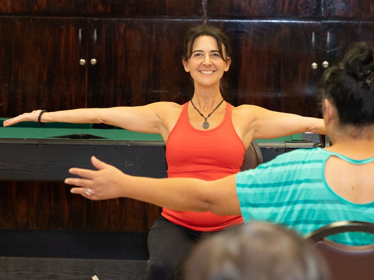 Nikki faces a participant, both extending their arms out to the sides.